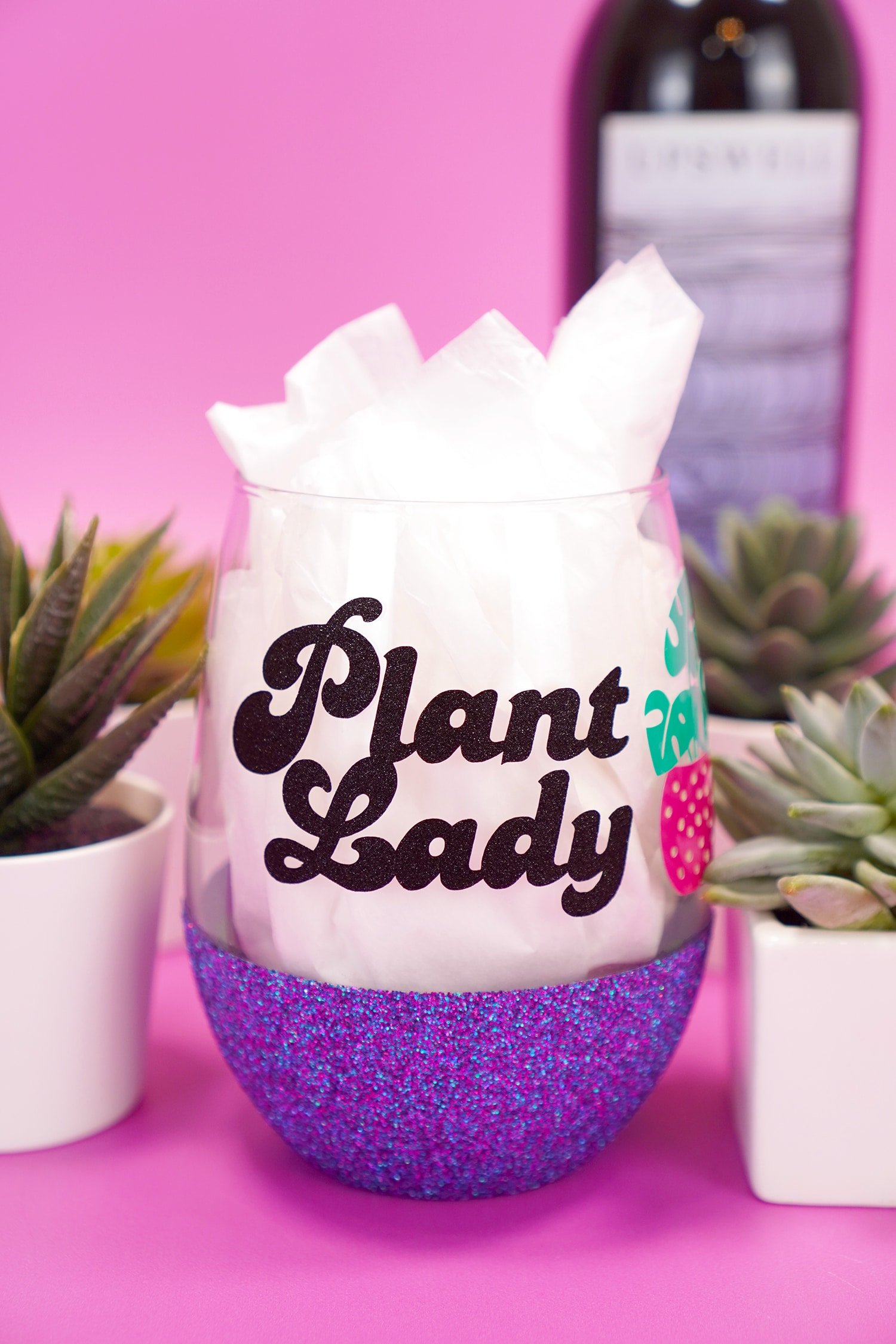 "Plant Lady" glitter wine glass on purple background with wine bottle and plants in background