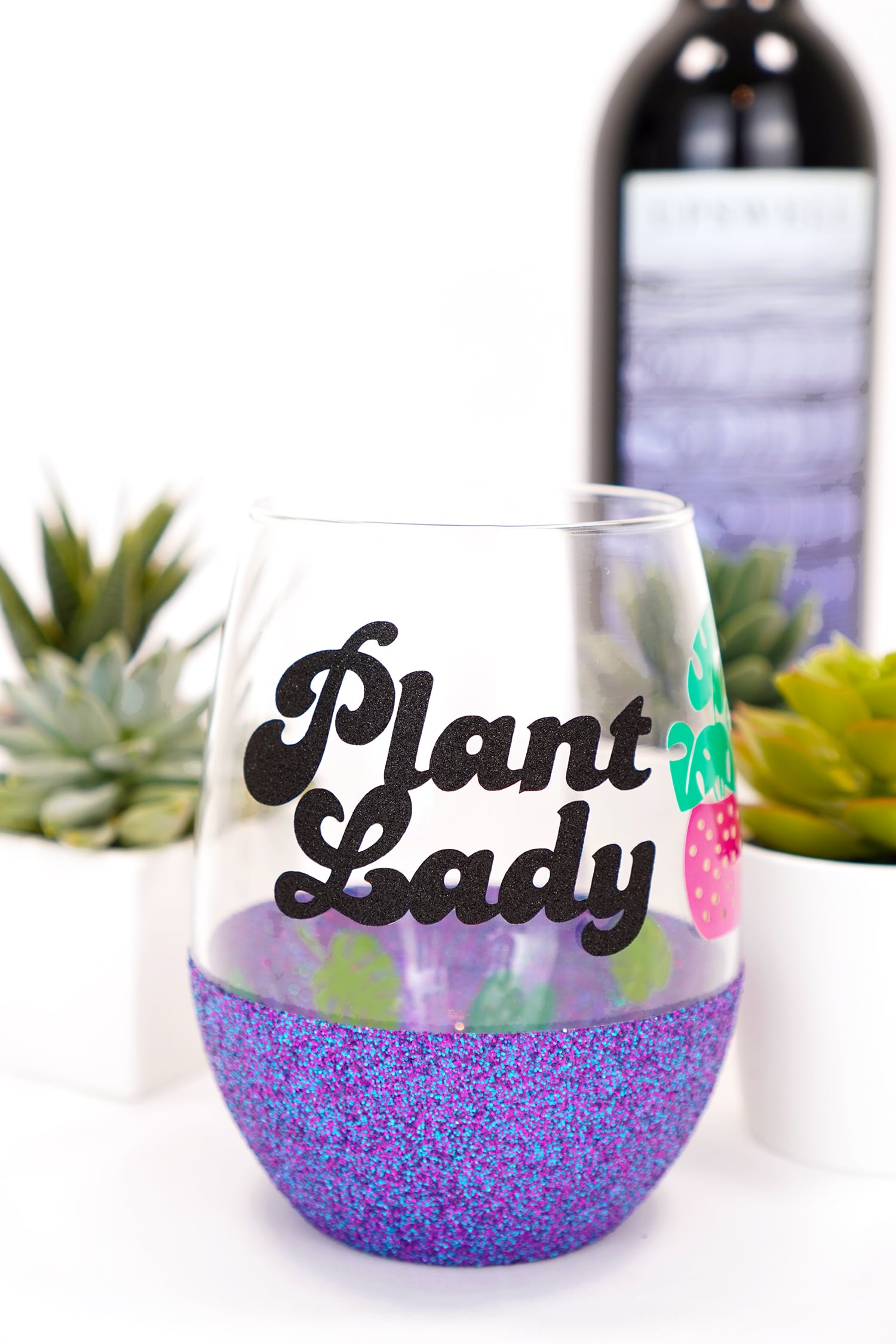 "Plant Lady" glitter wine glass with plants and wine bottle in background