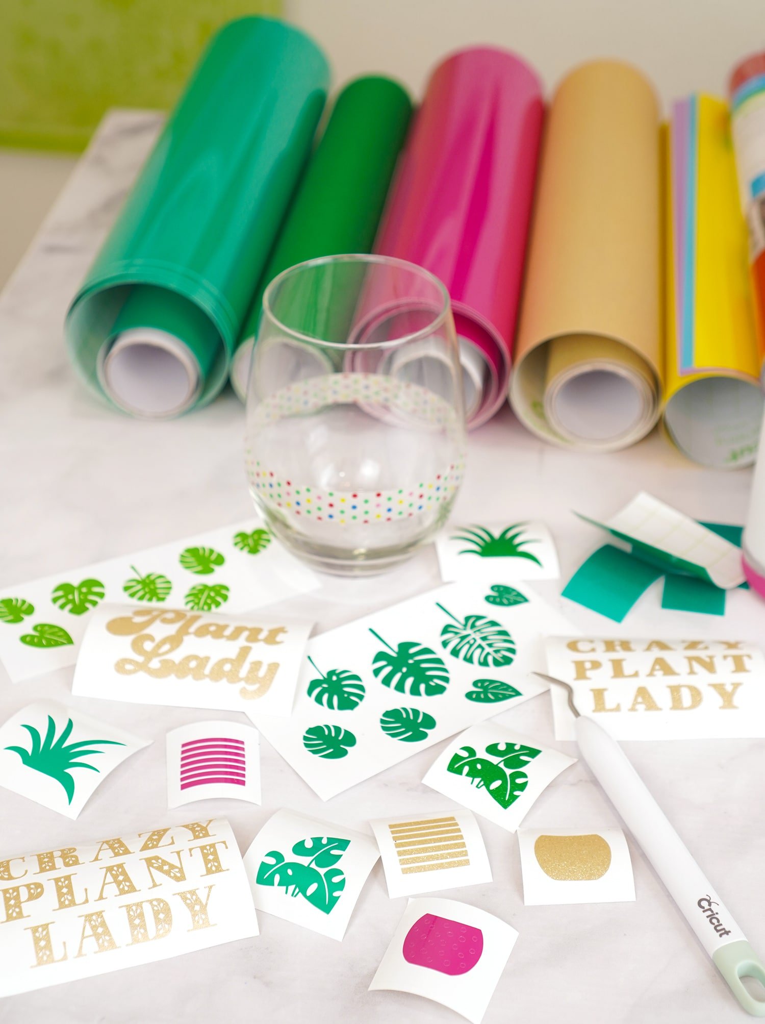 Weeded vinyl decals with weeding tool, vinyl rolls, and stemless wine glass