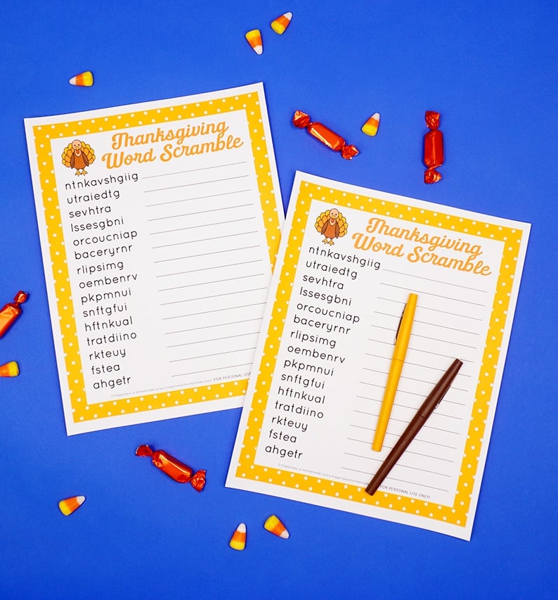 Two printable Thanksgiving Word Scrambles on a blue background surrounded by candy and a yellow and brown pen. 