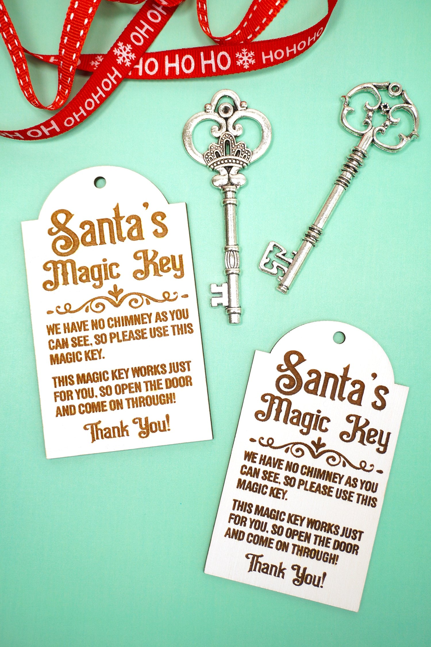 Two Santa's Magic Key tags with red ribbons and silver keys on a mint green background