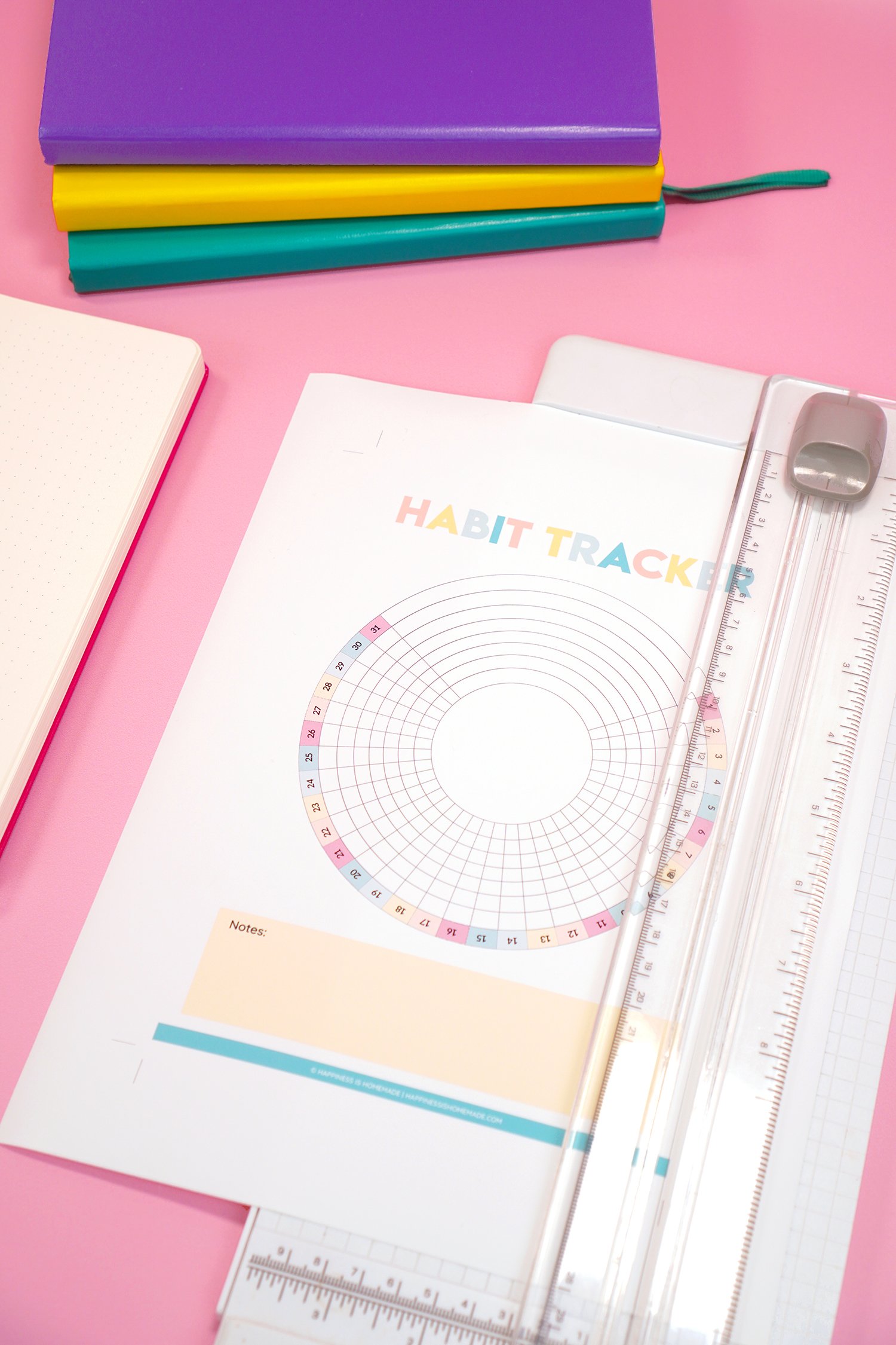 Printable Habit Tracker sheet in white paper cutter on pink background with bullet journals