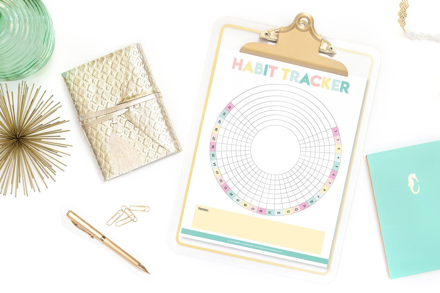 Printable circle habit tracker on gold clipboard on white background with gold wallet, gold pen, and gold paperclips