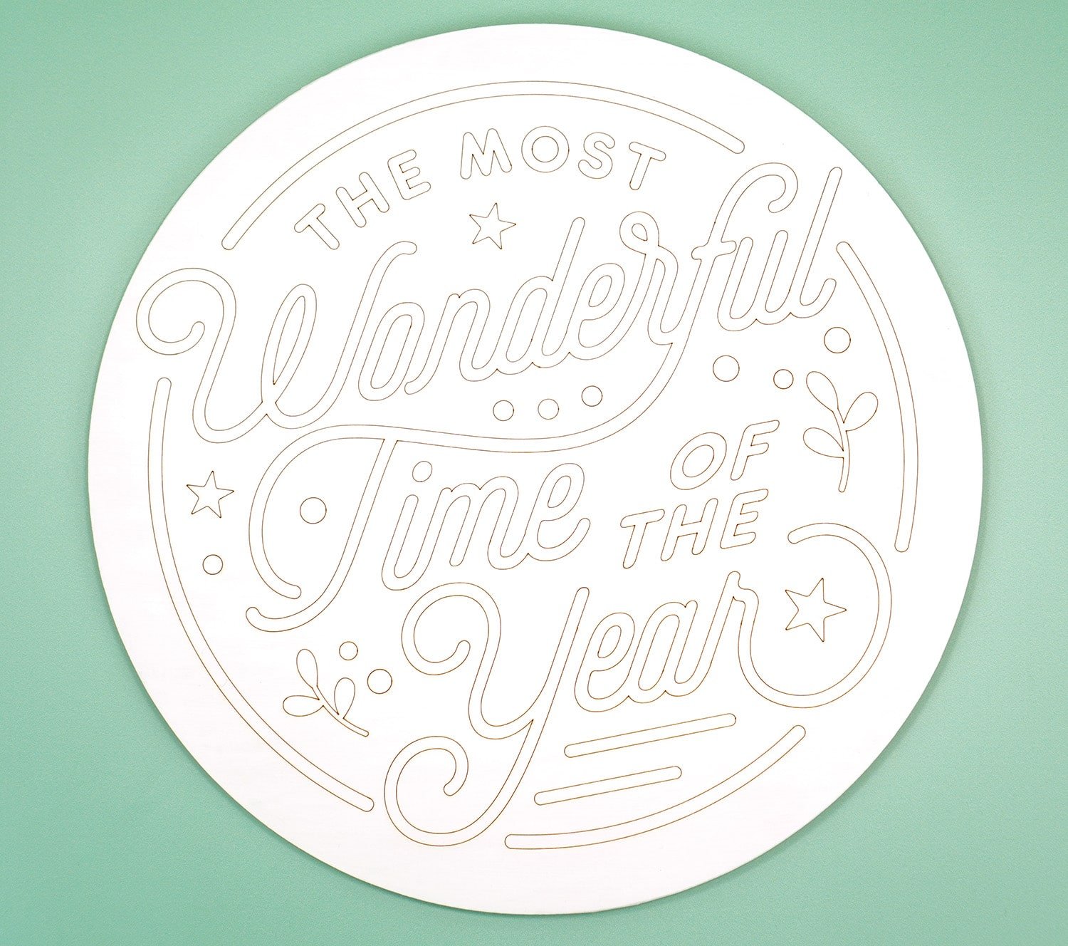 Round white wood sign with "The Most Wonderful Time of the Year" scored into it with a Glowforge laser