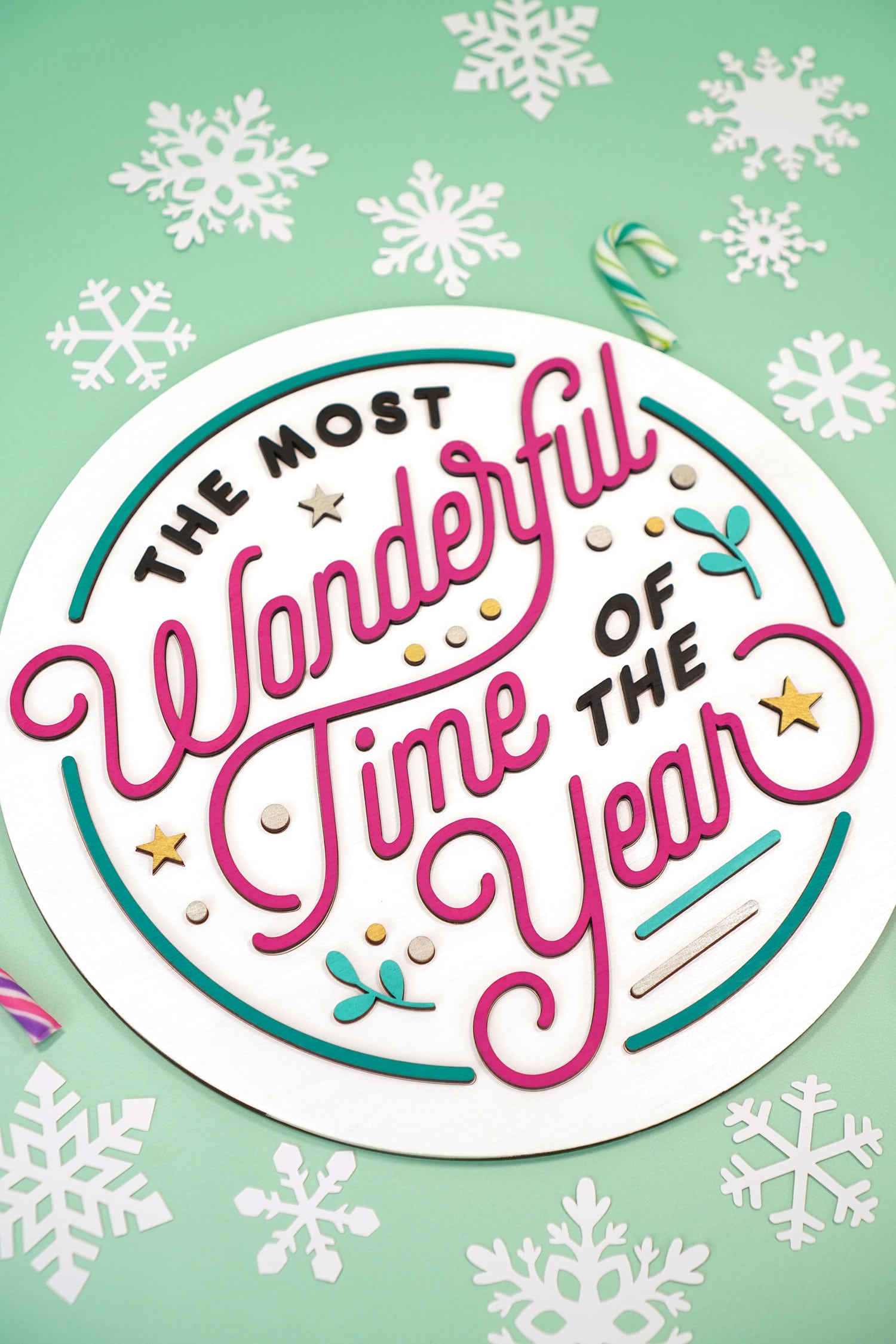 "The Most Wonderful Time of the Year" Laser Cut Wood Sign on mint green background with paper snowflakes and candy canes