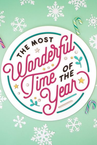 "The Most Wonderful Time of the Year" Laser Cut Wood Sign on mint green background with white paper snowflakes and colorful mini candy canes