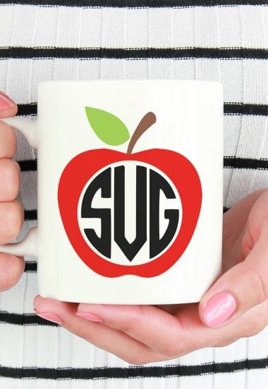 Close up of hands holding white mug with red apple design and monogram SVG