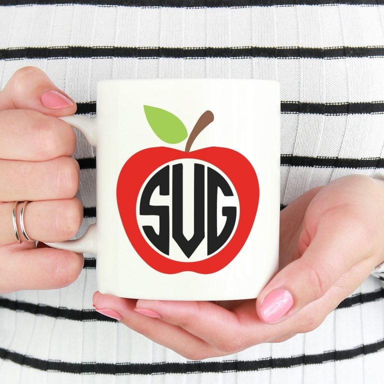 Close up of hands holding white mug with red apple design and monogram SVG
