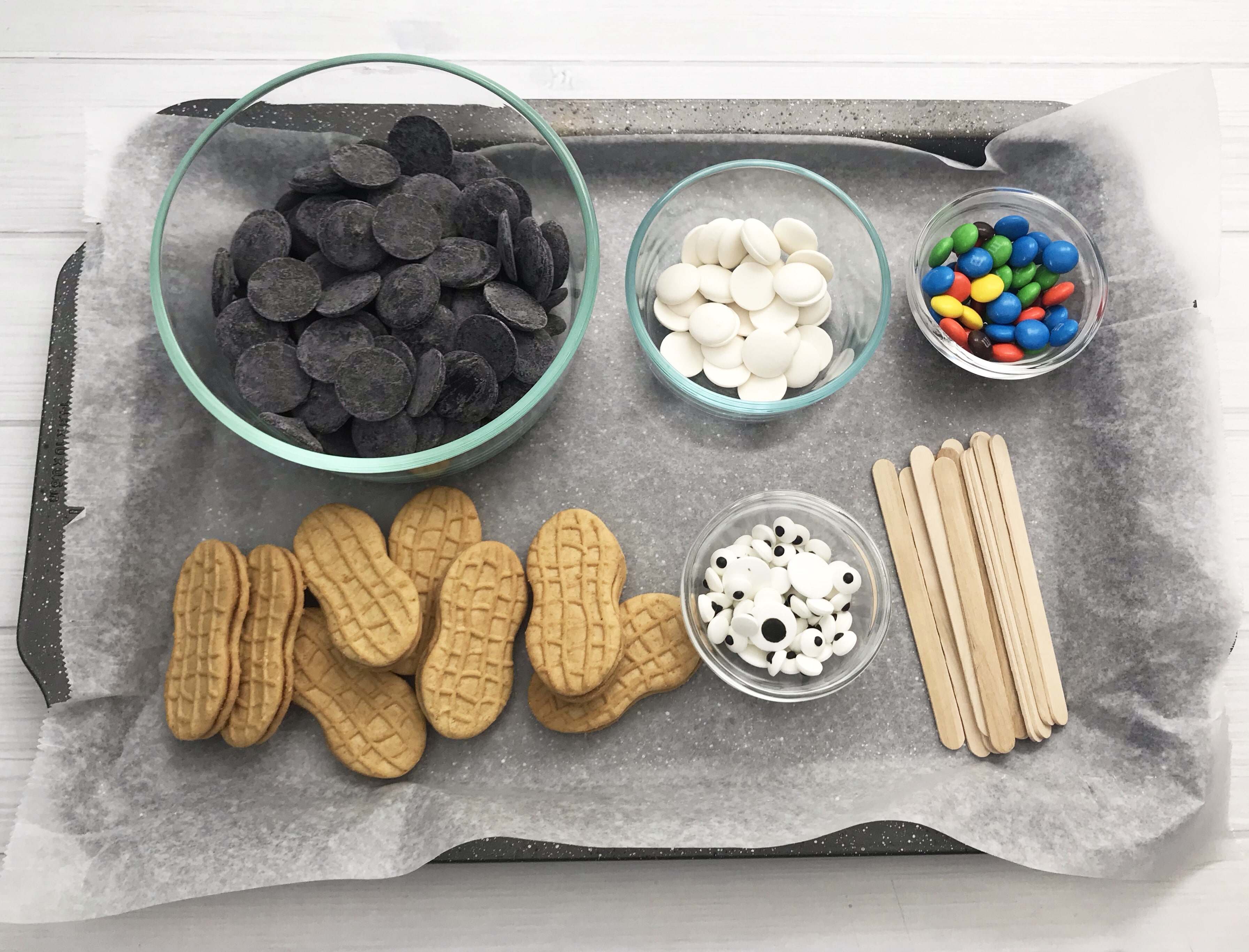 Ingredients to make nutter butter penguin cookies on a baking tray