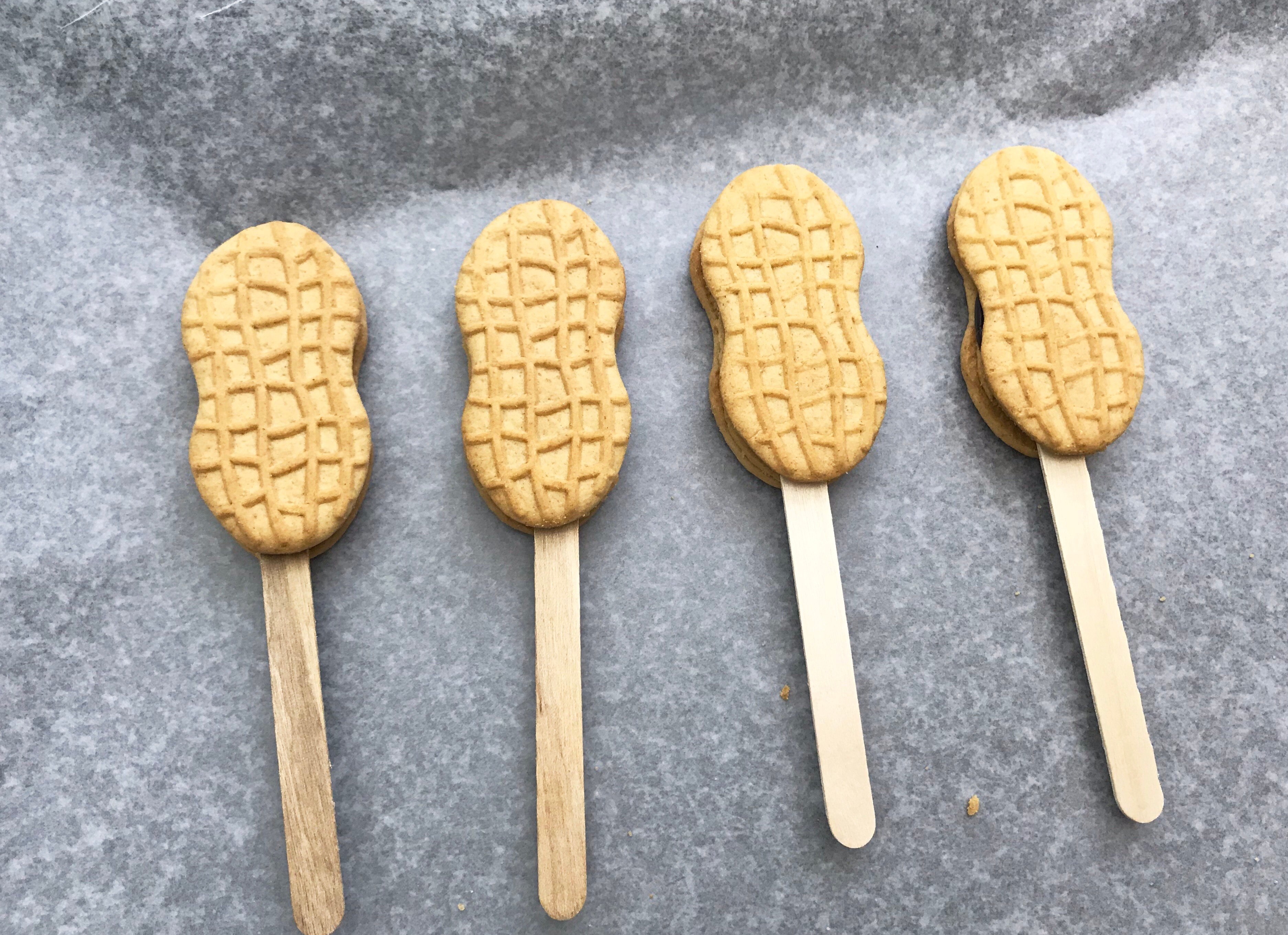 4 nutter butter coookies with popsicle sticks on a grey background