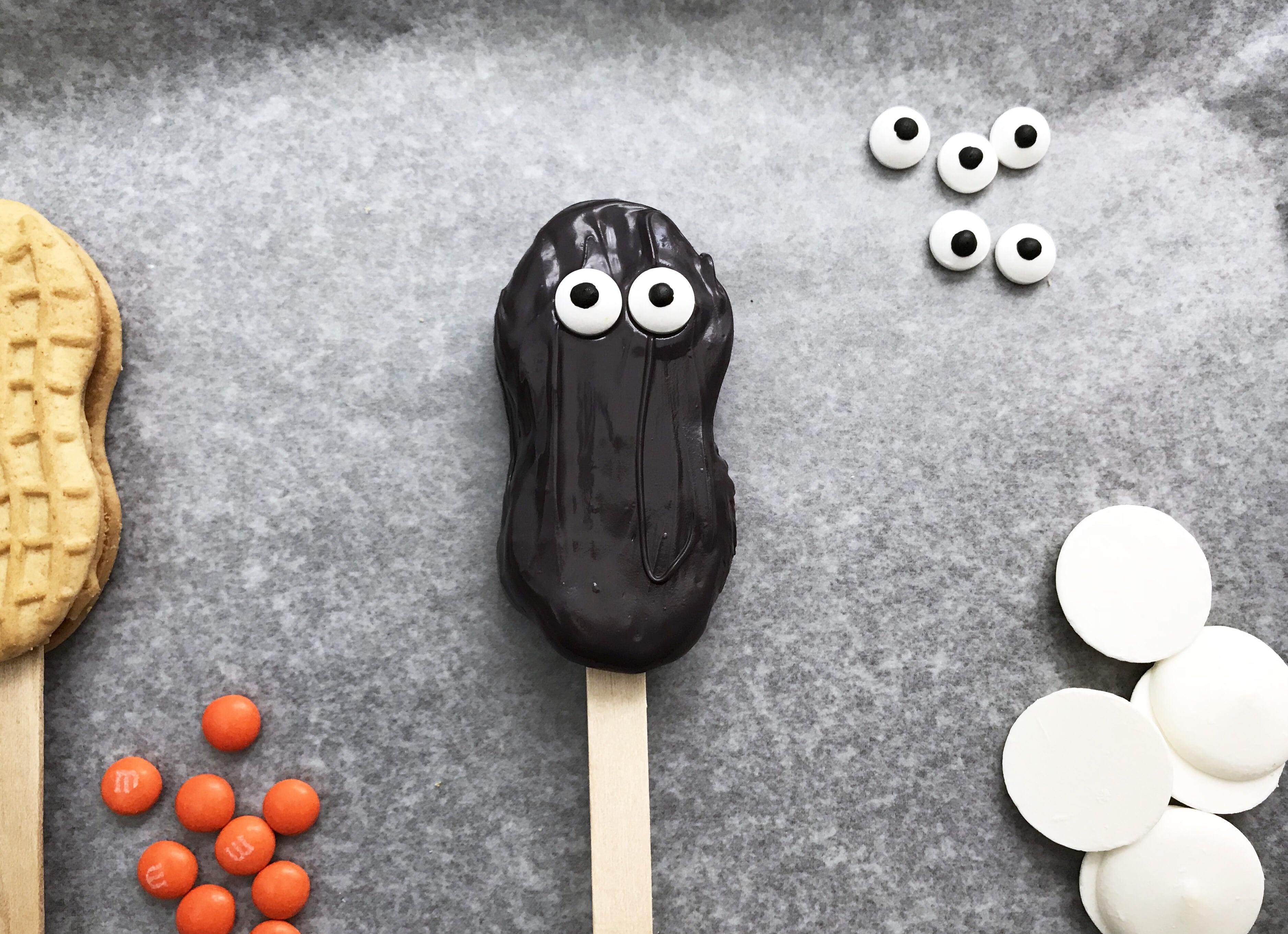 black icing covered nutter butter cookie pop with google eyes