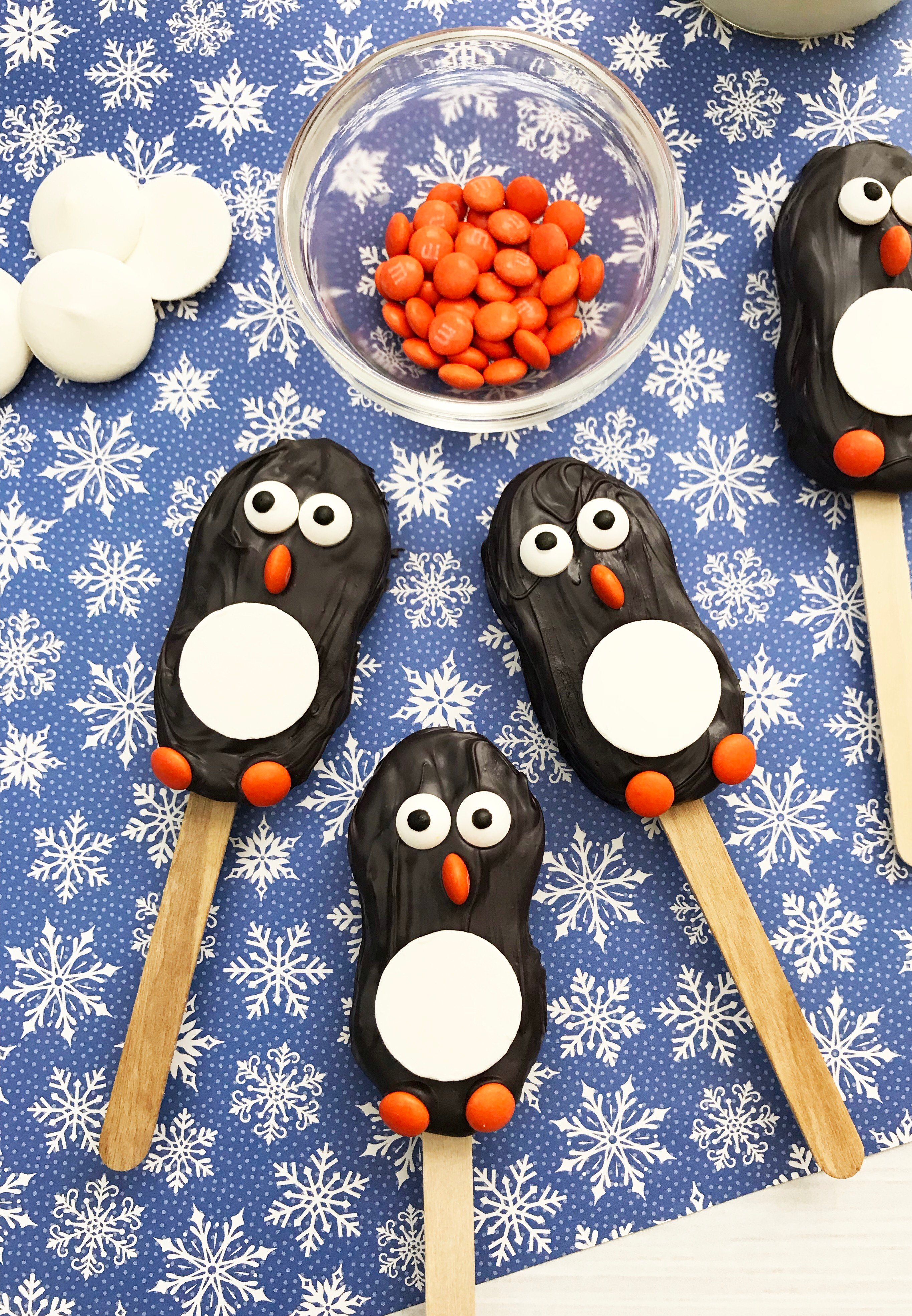 3 penguin cookies on a blue background with snowflakes