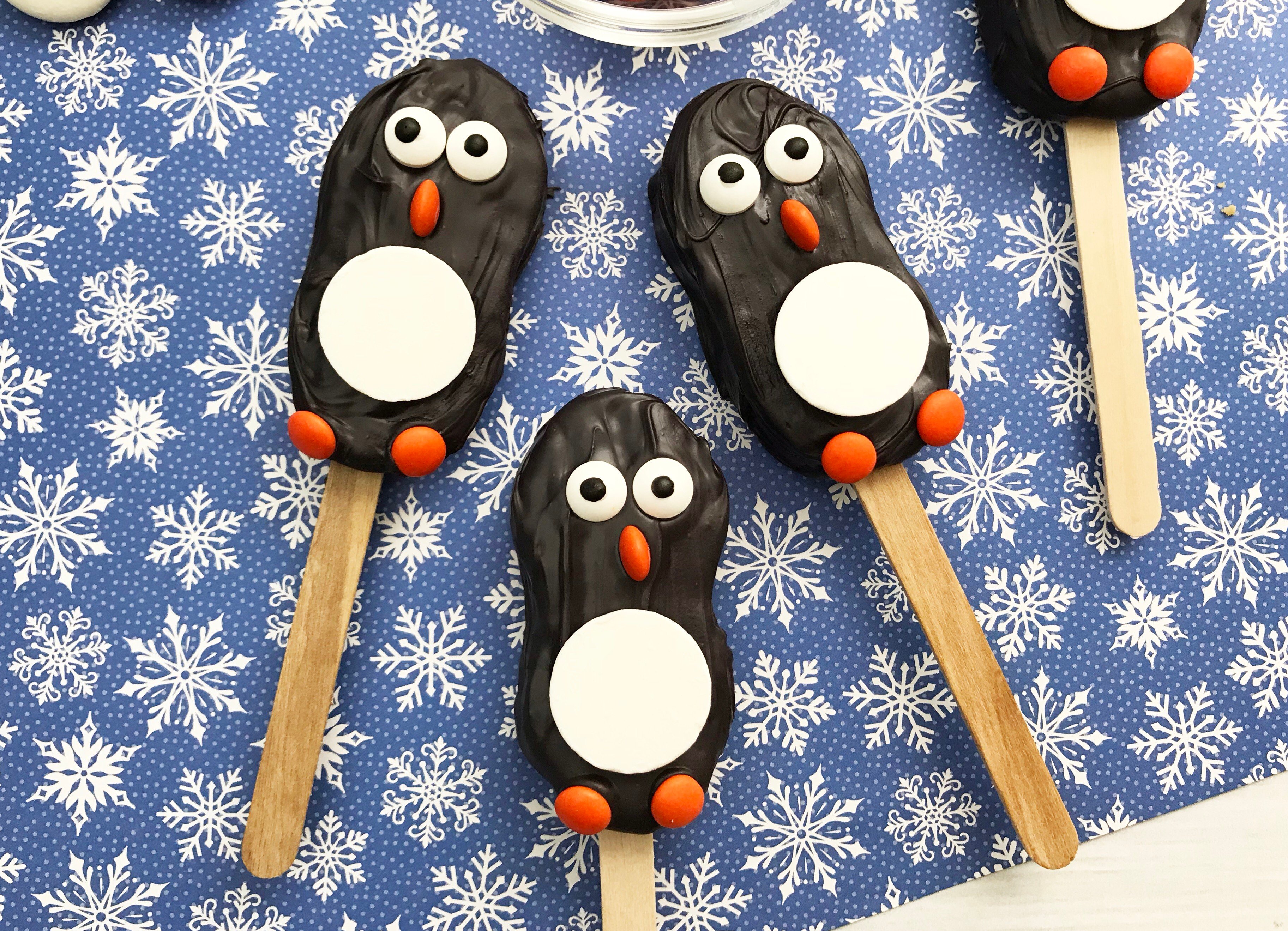 Penguin Nutter Butter Cookies on Blue Background with White Snowflakes