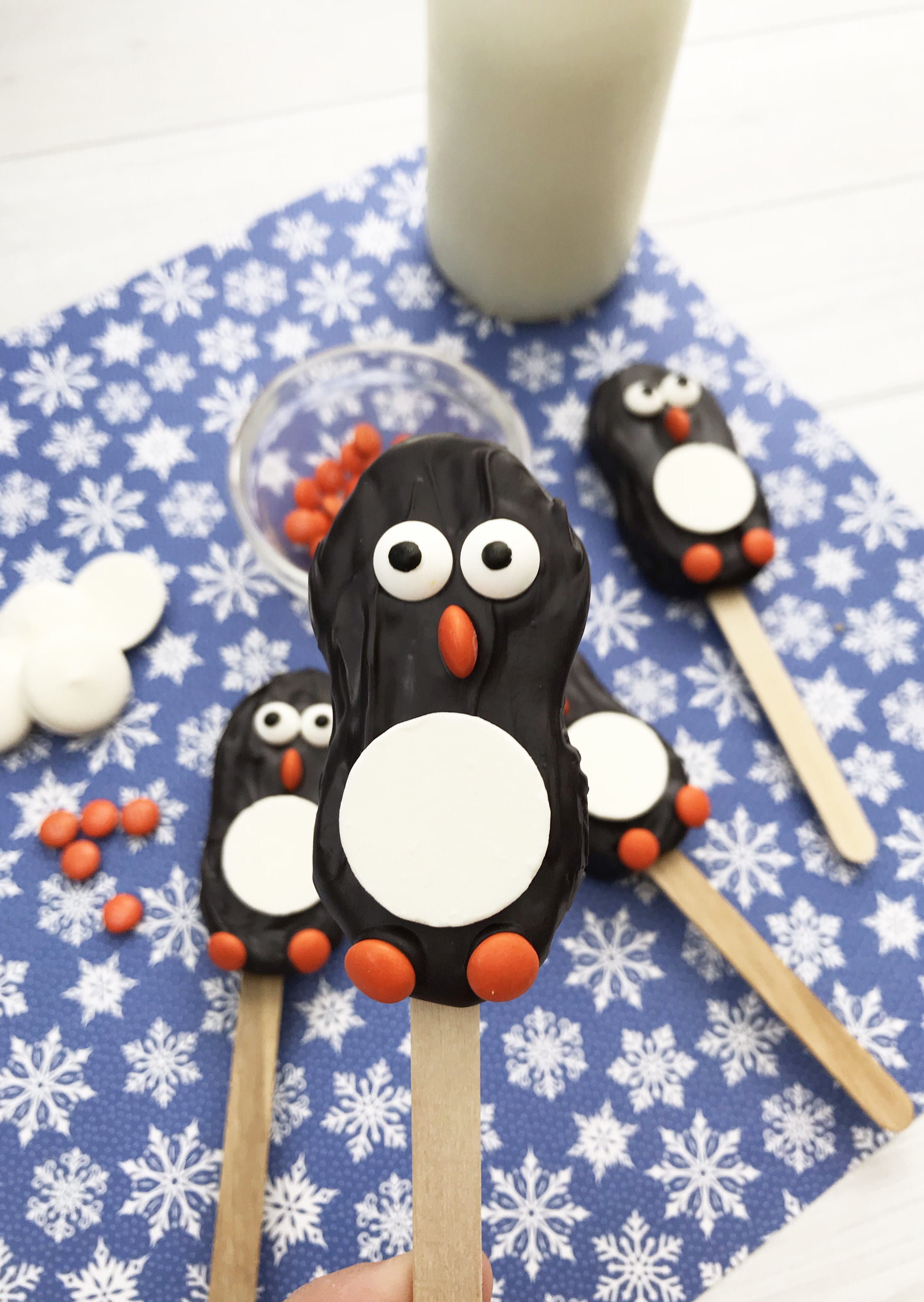 nutter butter cookie pops with glass of milk on blue background with snowflakes