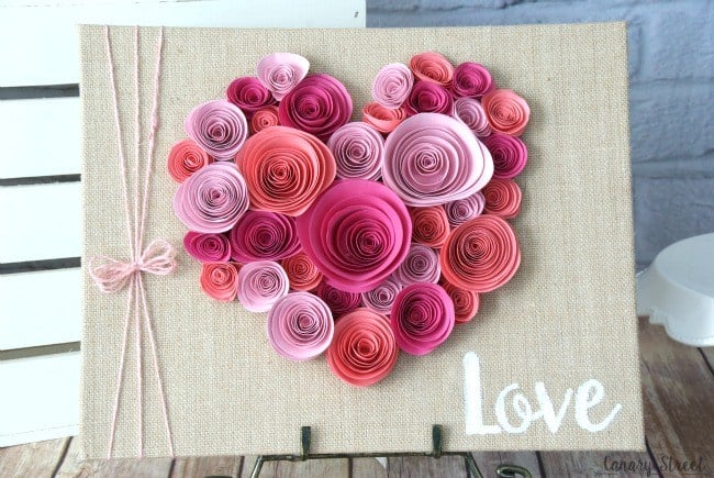 rolled paper flowers styled as a heart on sign that reads love