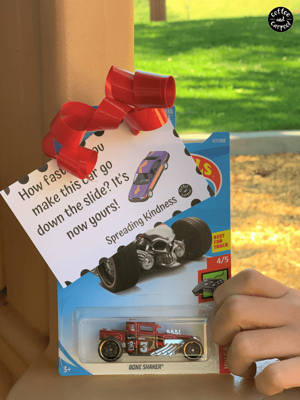 person holding toy car with printable spreading kindness tag