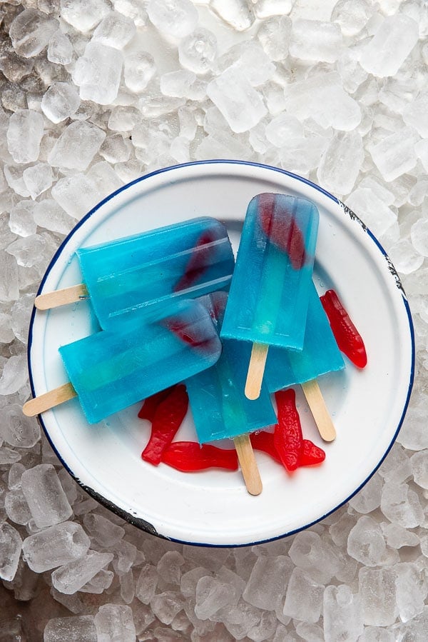 frozen diy blue lagoon cocktail popsicles in a bowl with swedish fish