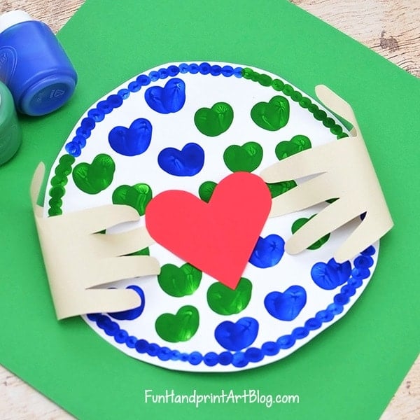 hands hugging paper plate earth