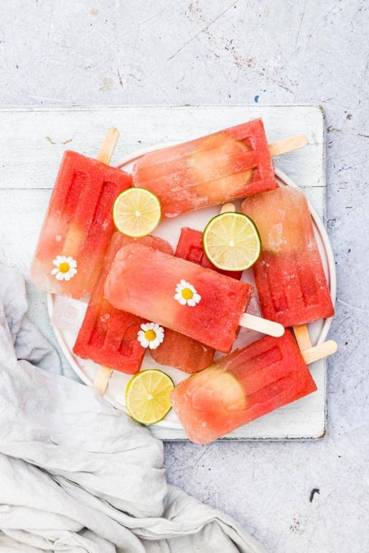 salted watermelon margarita popsicles with limes and flowers