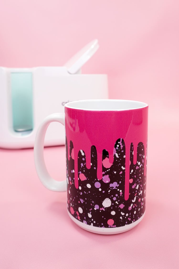 Pink and black "drippy" Infusible Ink mug on pink background with Cricut Mug Press