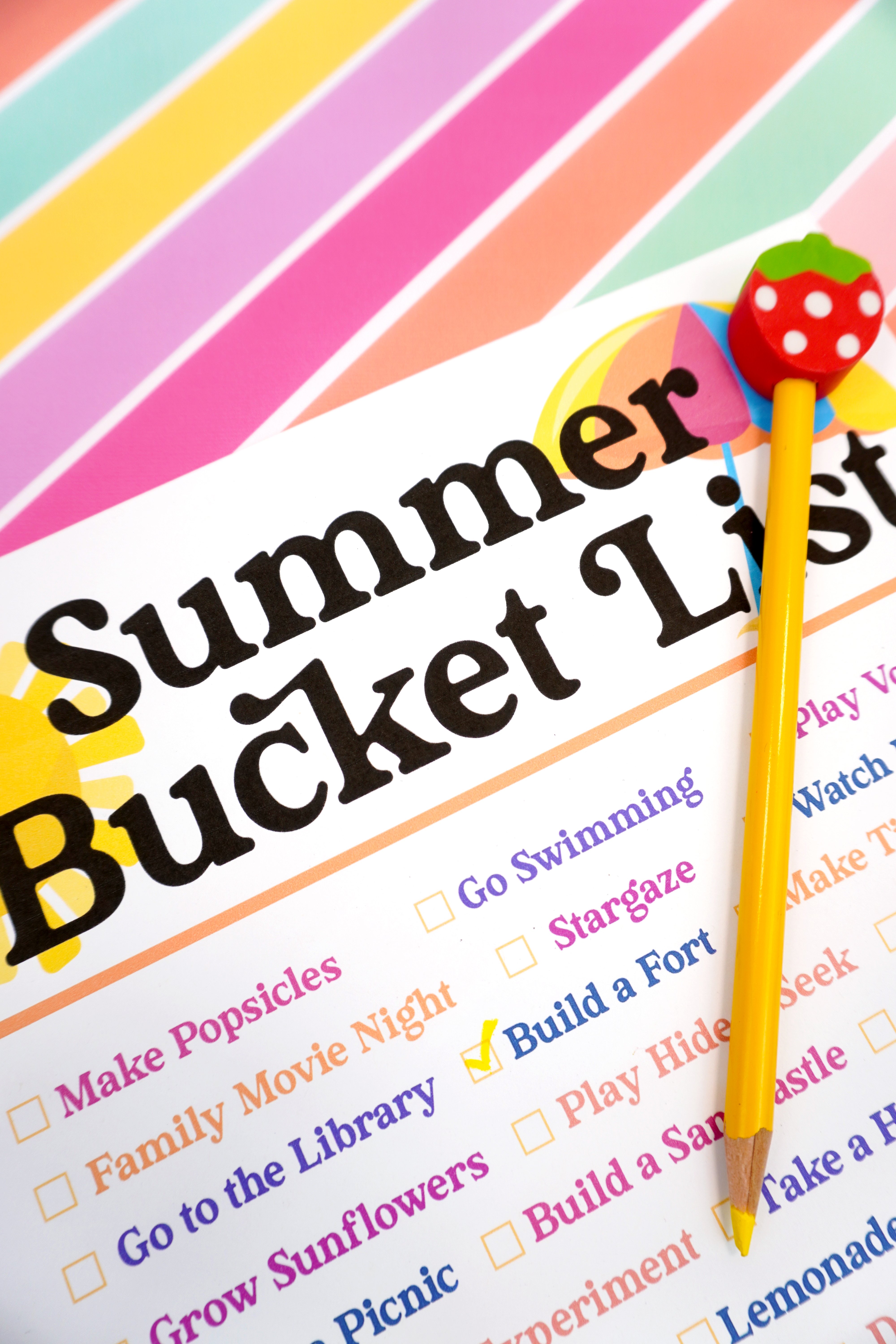 Close up of yellow pencil with strawberry eraser on top of a Summer Bucket List printable