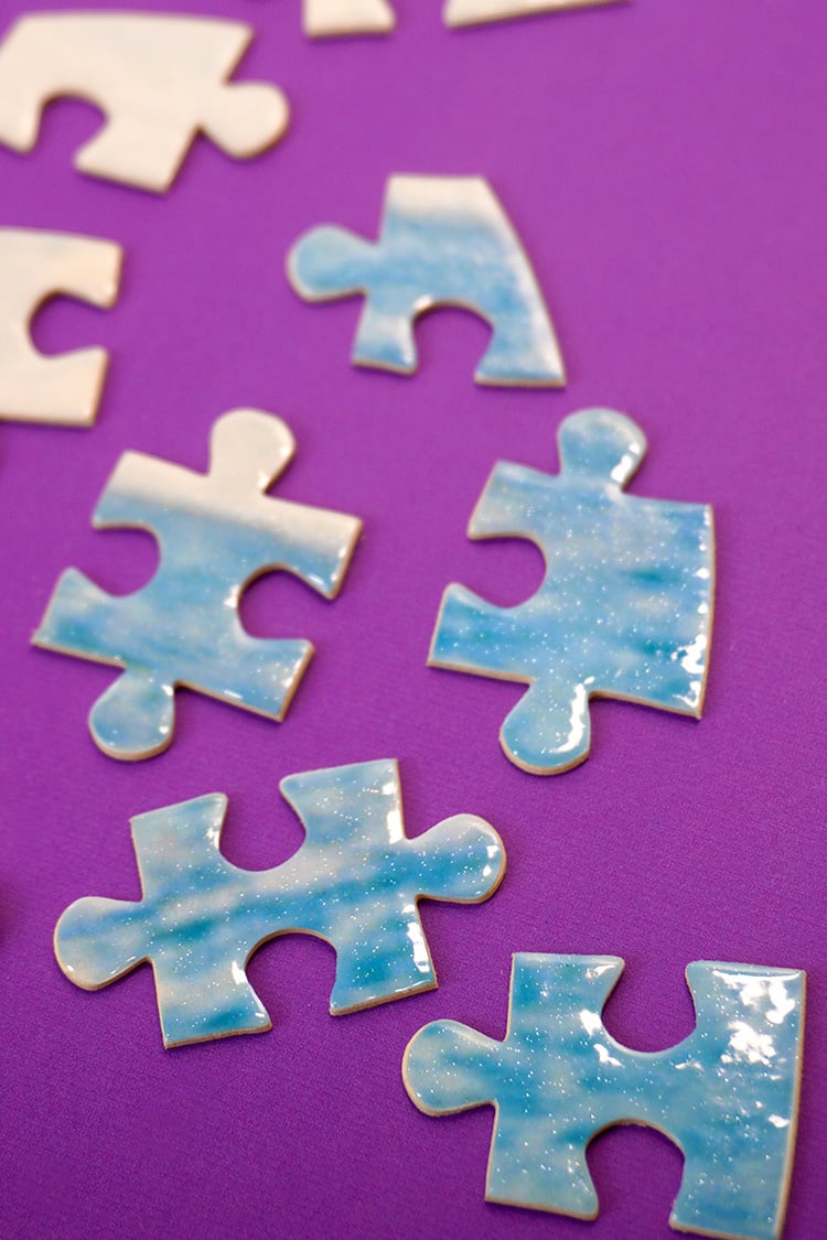 Close up of glossy finished puzzle pieces with pearlescent glitter finish on purple background