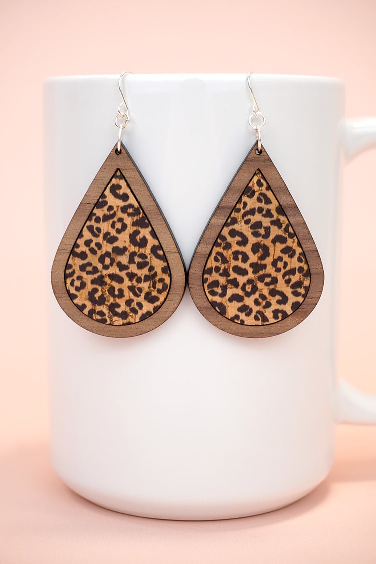 Leopard print laser cut wood earrings displayed on white mug