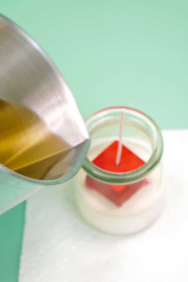 Pouring wax from a candle pitcher into a candle jar