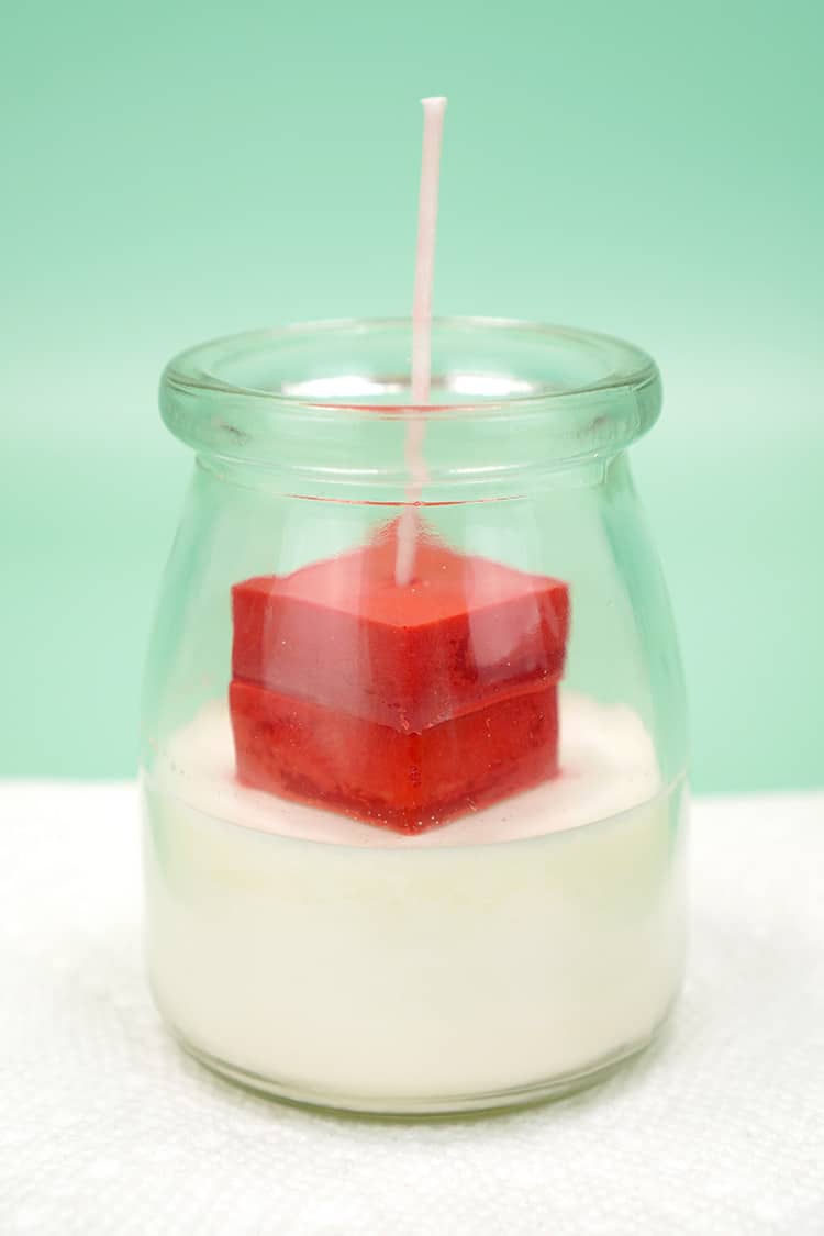 Candle jar with blocks of red wax on green background