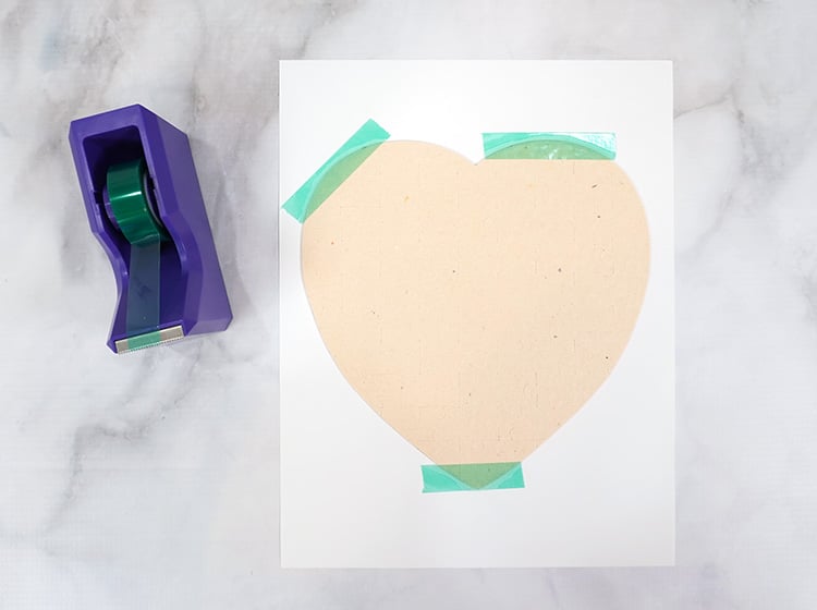 Heart shaped puzzle on top of paper with green heat resistant tape holding them in place