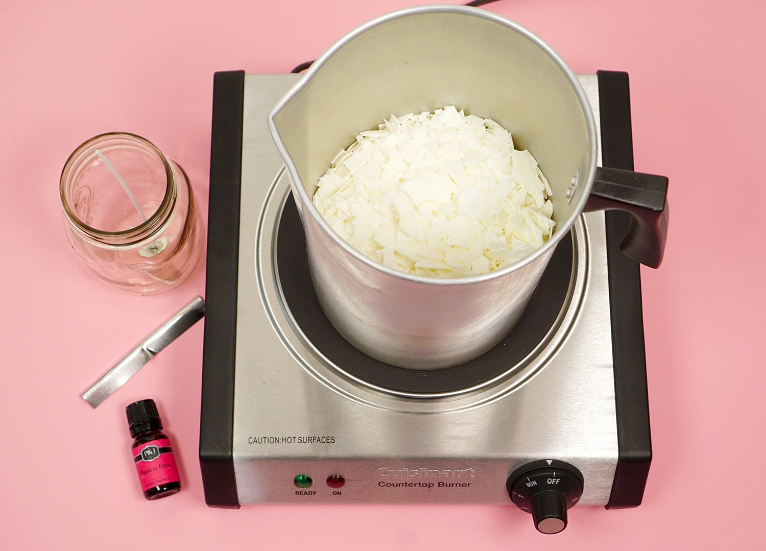 Soy wax flakes in melting pot surrounded by candle making supplies