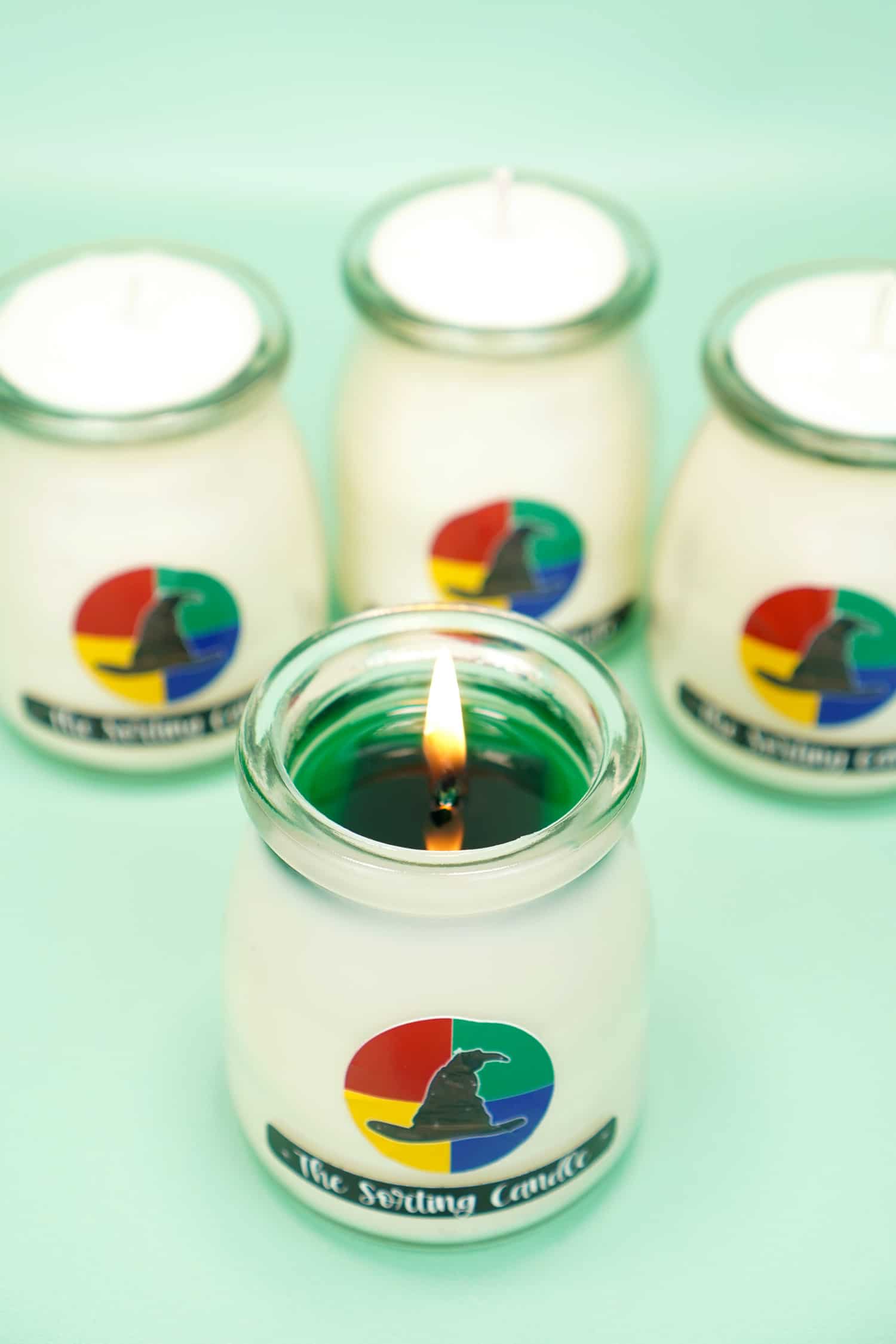 White Sorting Candle burning with Slytherin Green Wax with three candles in background