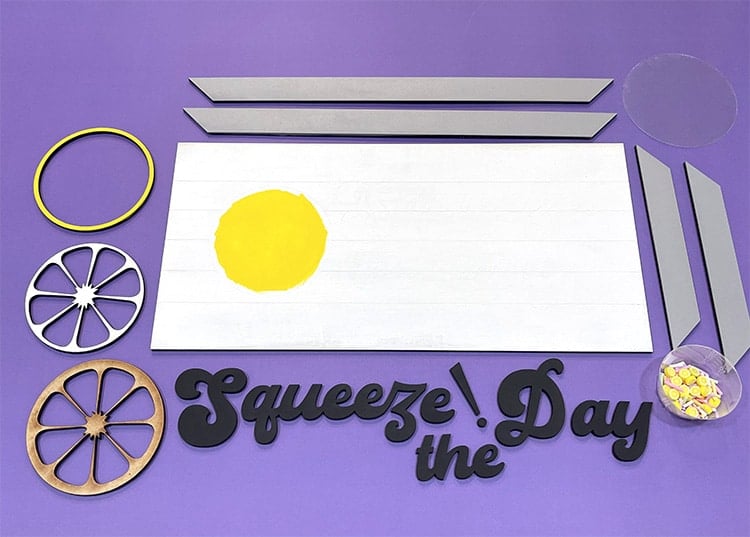 Painted laser cut wood sign pieces on a purple background