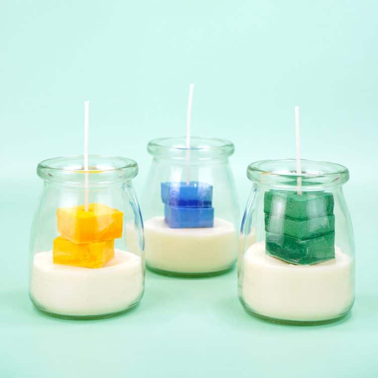 Three candles with yellow, blue, and green colored blocks of wax