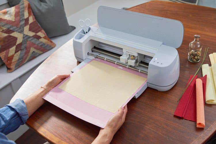 hands feeding cutting mat into cricut machine