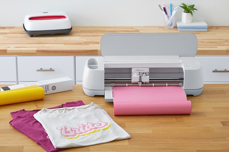 Cricut Maker 3 machine with pink Smart Vinyl on desk with other Cricut materials
