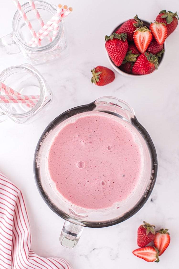 Overhead view of freshly blended pink strawberry milkshake in blender