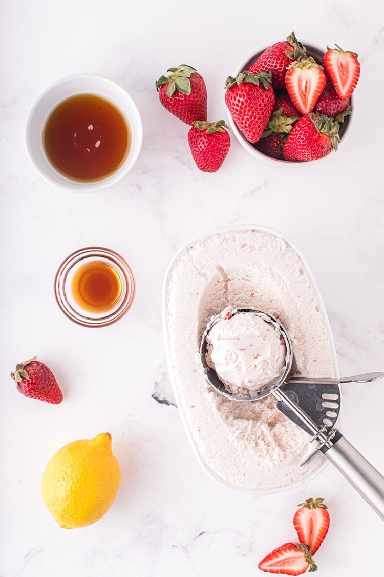 Overhead view of strawberry milkshake recipe ingredients on marble background