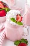 Close up of whipped cream and strawberry garnish on top of a strawberry milkshake