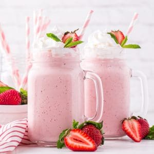 two strawberry milkshakes in glass cups