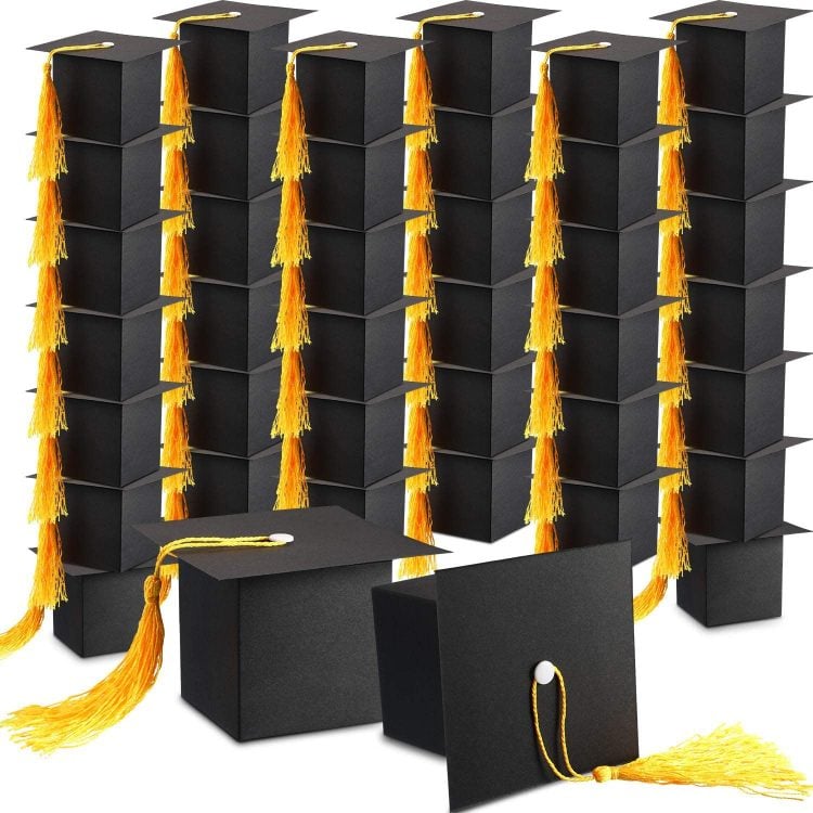 stackes of small black graduation hat shaped boxes with yellow tassels