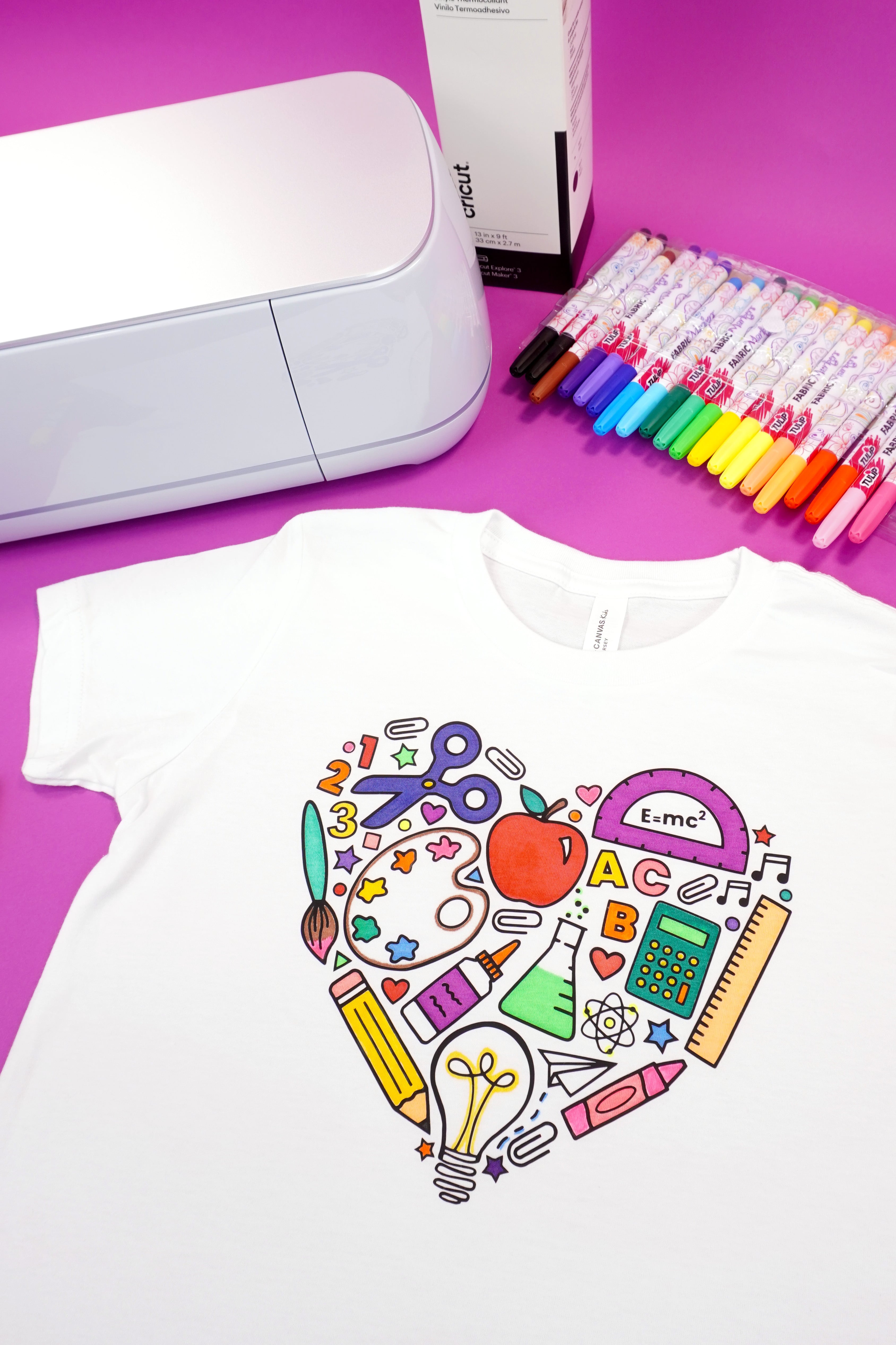 Back to school coloring shirt on a purple background with fabric markers, Cricut Maker 3, and Smart Iron-On