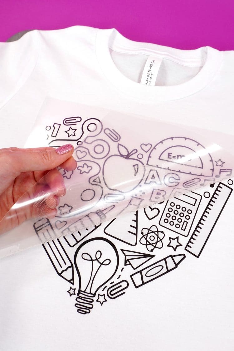 Hand peeling back heat transfer vinyl backing from shirt