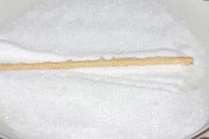 wooden skewer being rolled in a plate of sugar
