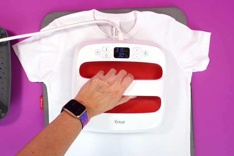 Hand using an EasyPress to apply iron-on to a white t-shirt