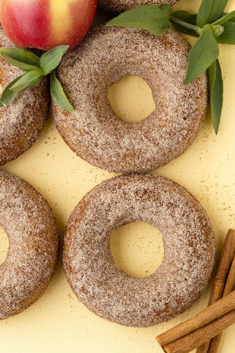 apple cinnamon donuts with apple and cinnamon sticks on a yellow background
