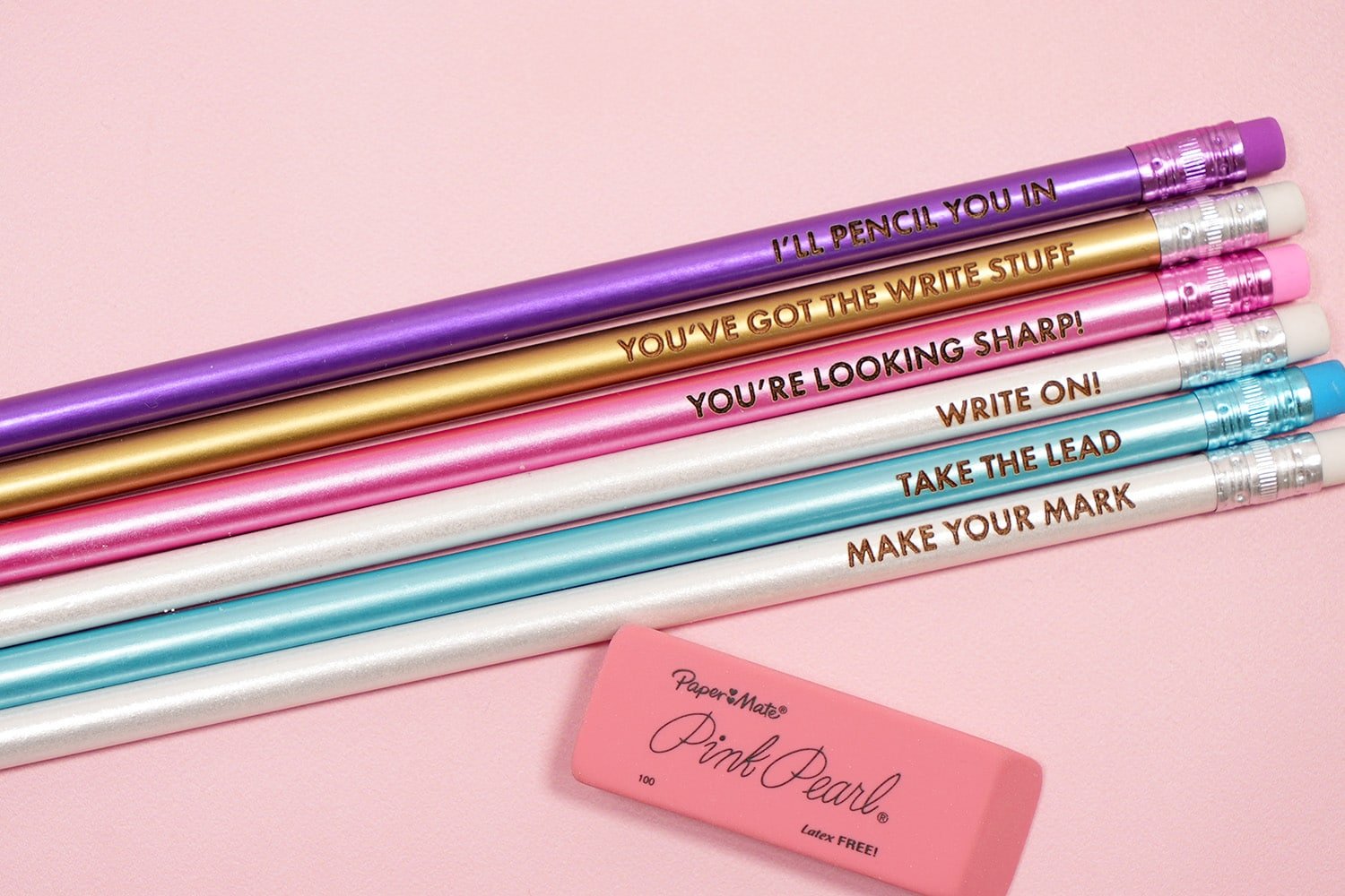 Colorful engraved pencils with pencil puns on a pink background with pink eraser