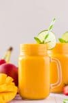 fresh mango smoothie in mason jar glass with lime wheel and striped straw