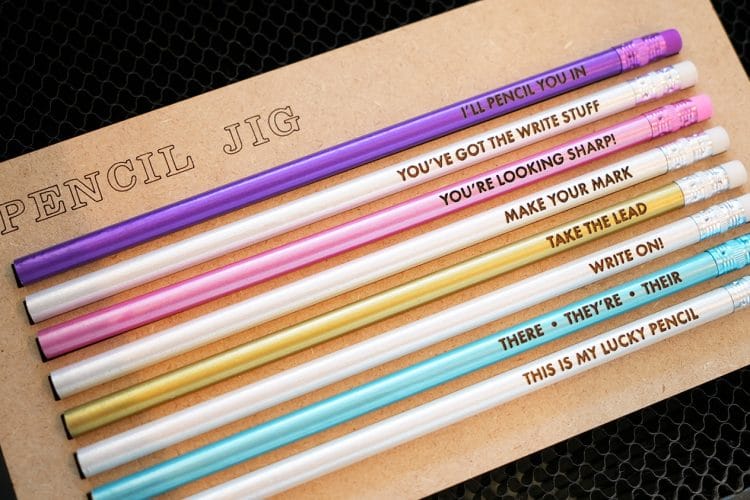 Glowforge pencil jig in machine with colorful engraved pencils