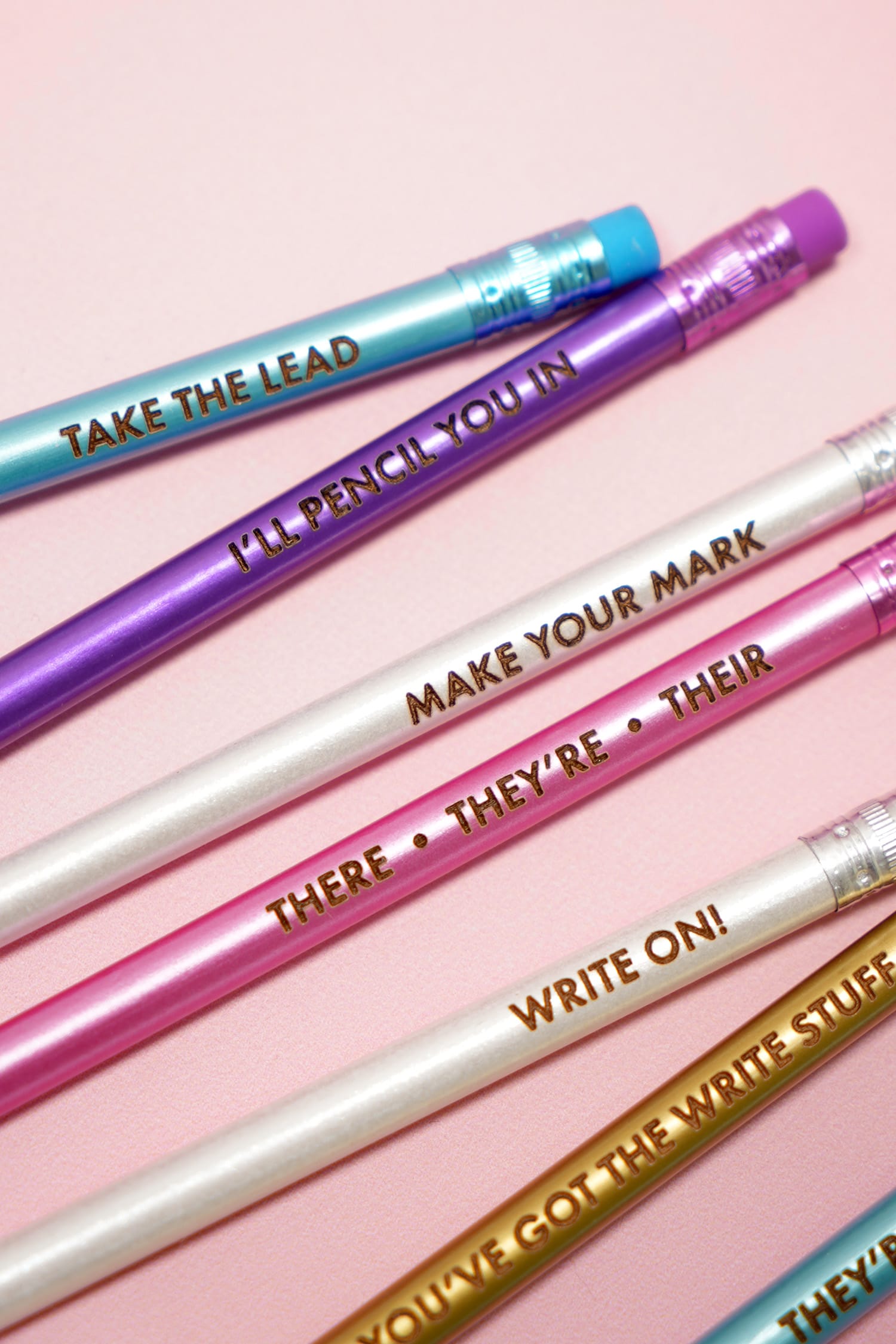 Close up of colorful Glowforge engraved custom pencils on a pink background